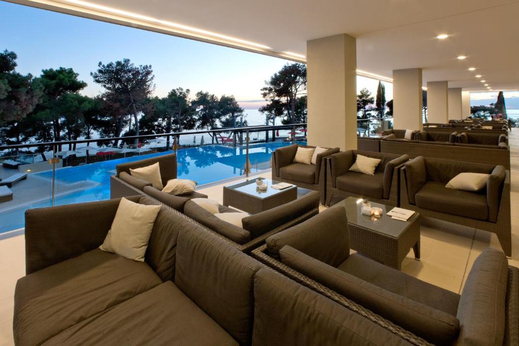 a living room with a large couch and a pool at Hotel Parentium Plava Laguna in Poreč