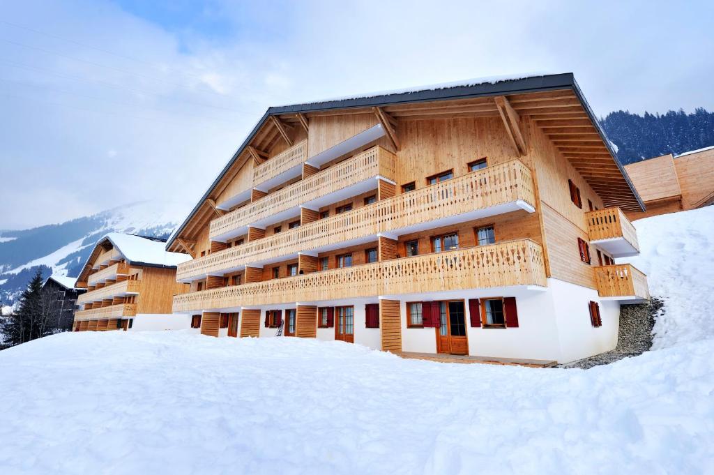 un grand bâtiment en bois dans la neige dans l'établissement Résidence Néméa Le Grand Lodge, à Châtel