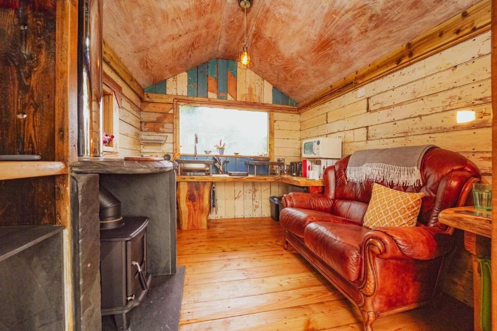 a living room with a leather couch in a cabin at Writing Shed Wales in Login