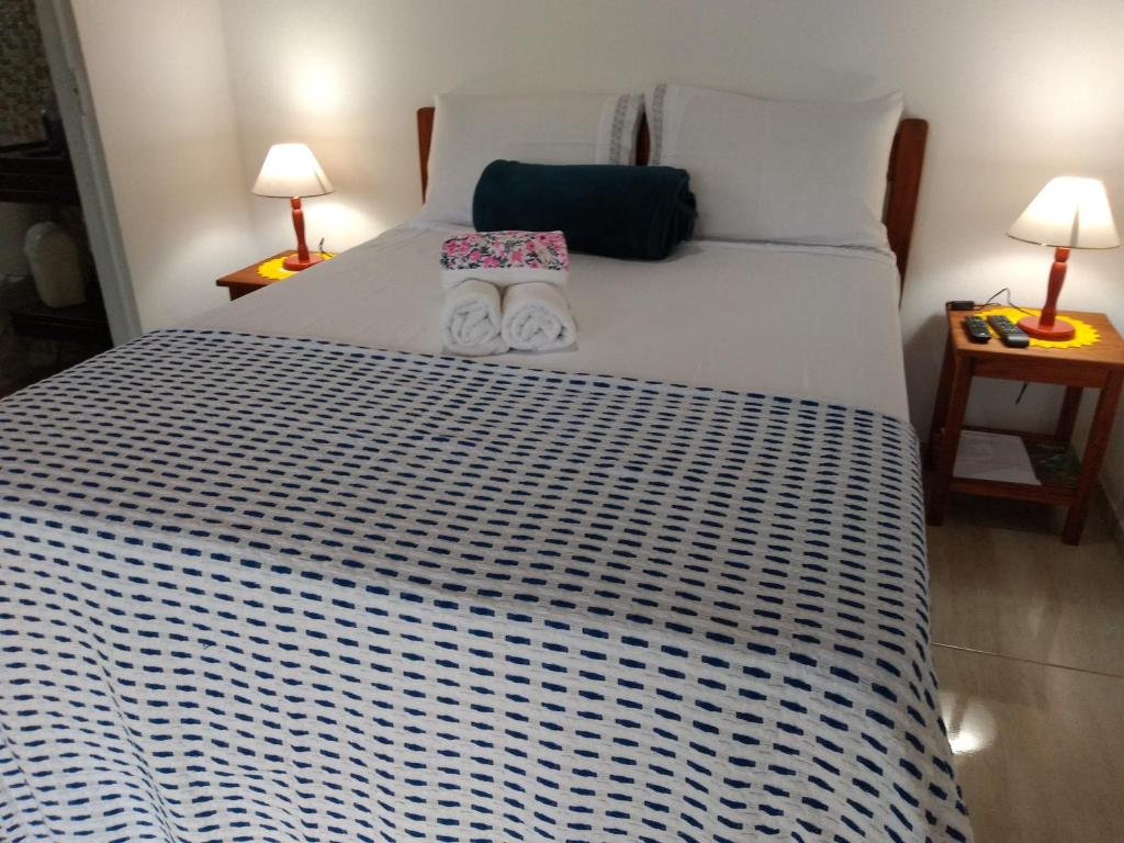 um quarto com uma grande cama branca e 2 candeeiros em Chalés Vale dos Pássaros em Paraty