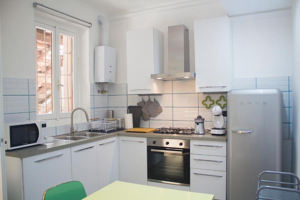 a white kitchen with white cabinets and a refrigerator at Rho-Fiera - Appartamento in antica cascina in Pero