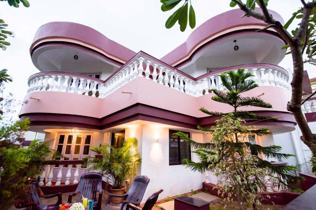 a pink house with a balcony and trees at 'Golden Sunset' 3bhk beach villa in Benaulim