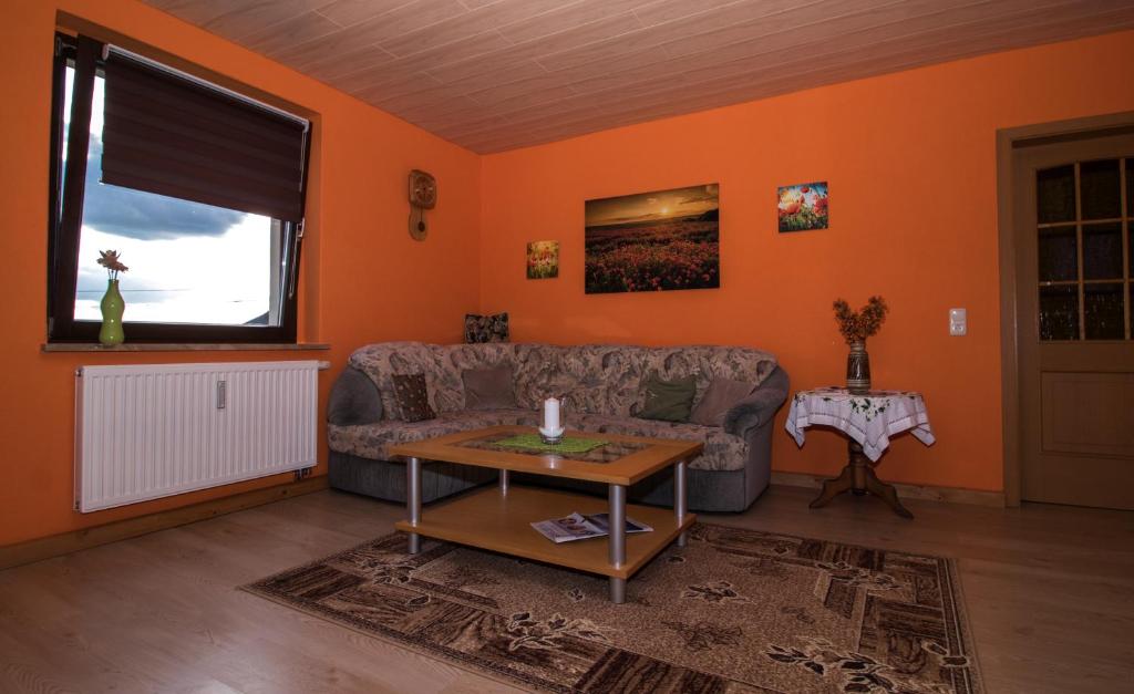 a living room with orange walls and a couch at am Balkon des Erzgebirges in Bernsbach