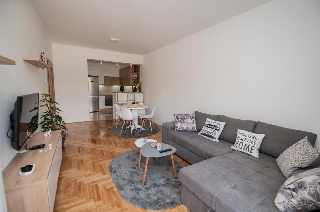 ein Wohnzimmer mit einem grauen Sofa und einem Tisch in der Unterkunft Cozy Apartment SINN in Trebinje