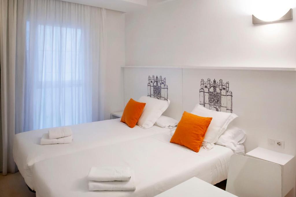 1 cama blanca con almohadas de color naranja y blanco en una habitación en Maria Salome en Burgos