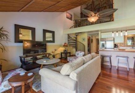 a living room with a white couch and a kitchen at KOA 3L in Kihei