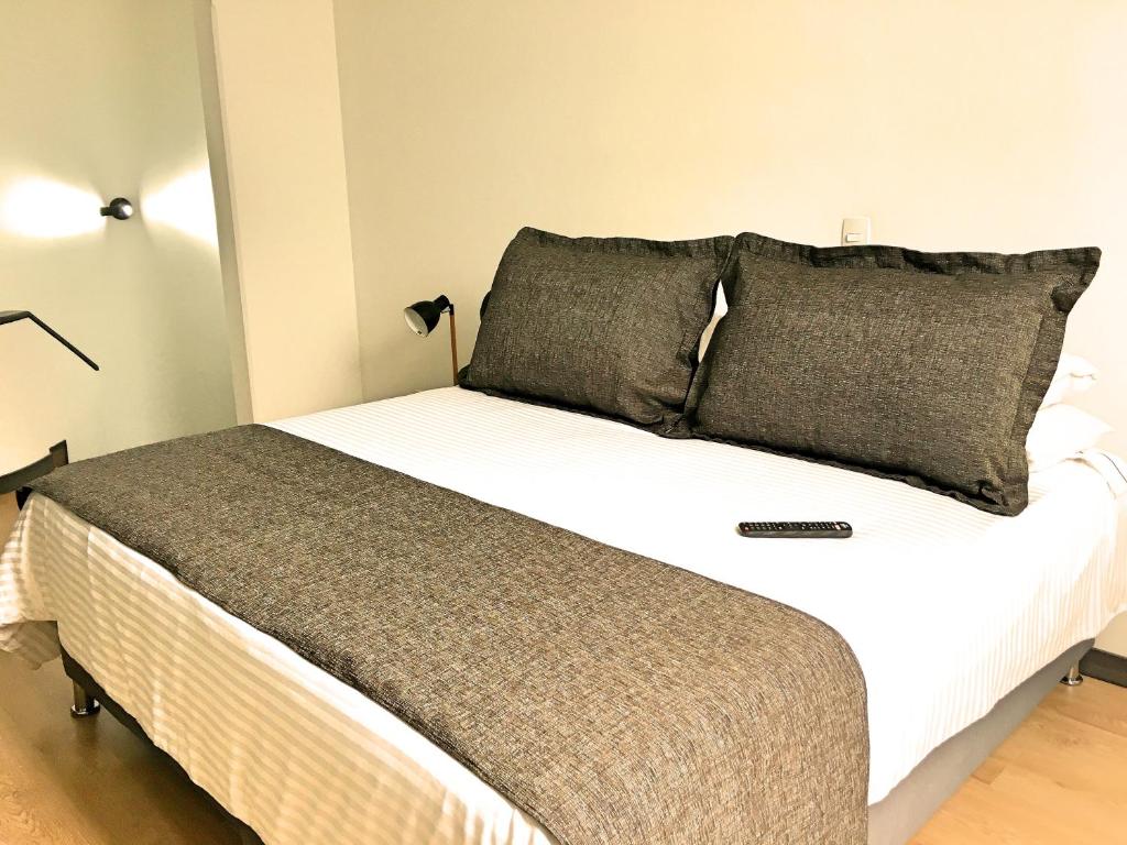 a bedroom with a bed with white sheets and gray pillows at Cora 96 Street Apartments in Bogotá
