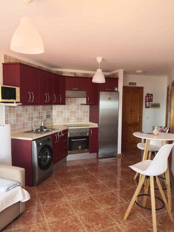 a kitchen with red cabinets and a sink and a table at Ecorestinga in La Restinga