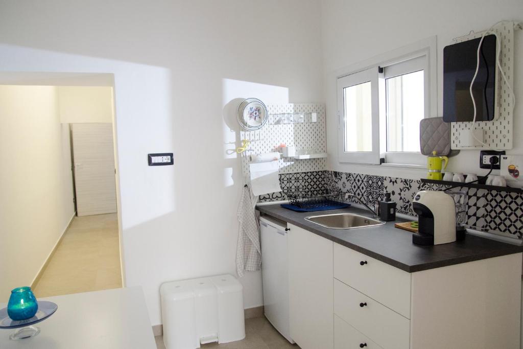 uma cozinha branca com um lavatório e uma bancada em Donna Nunzia Home em Noto