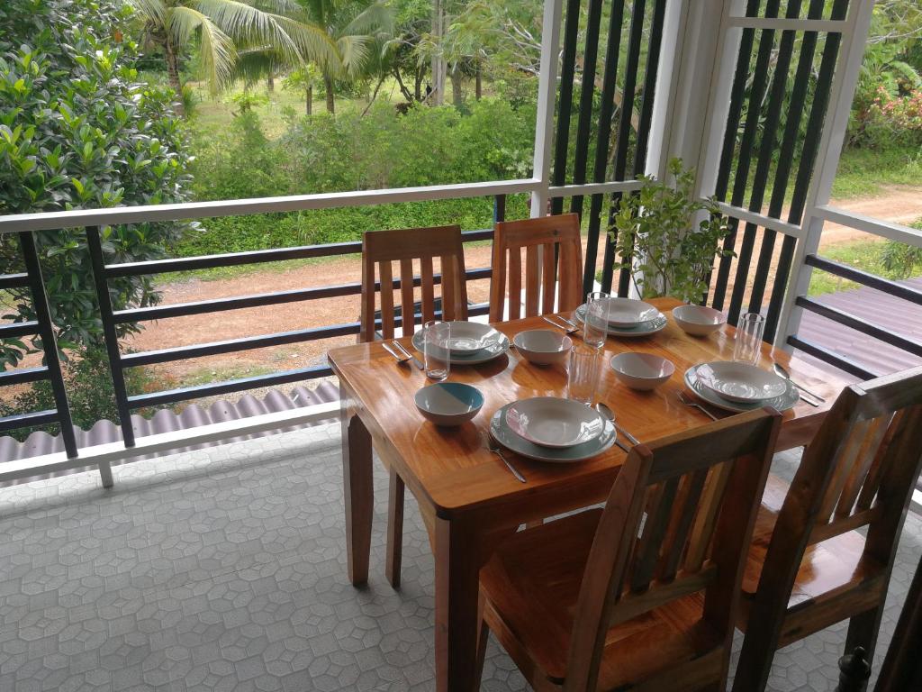 een houten tafel met borden en borden op een veranda bij Palm Garden House in Koh Lanta