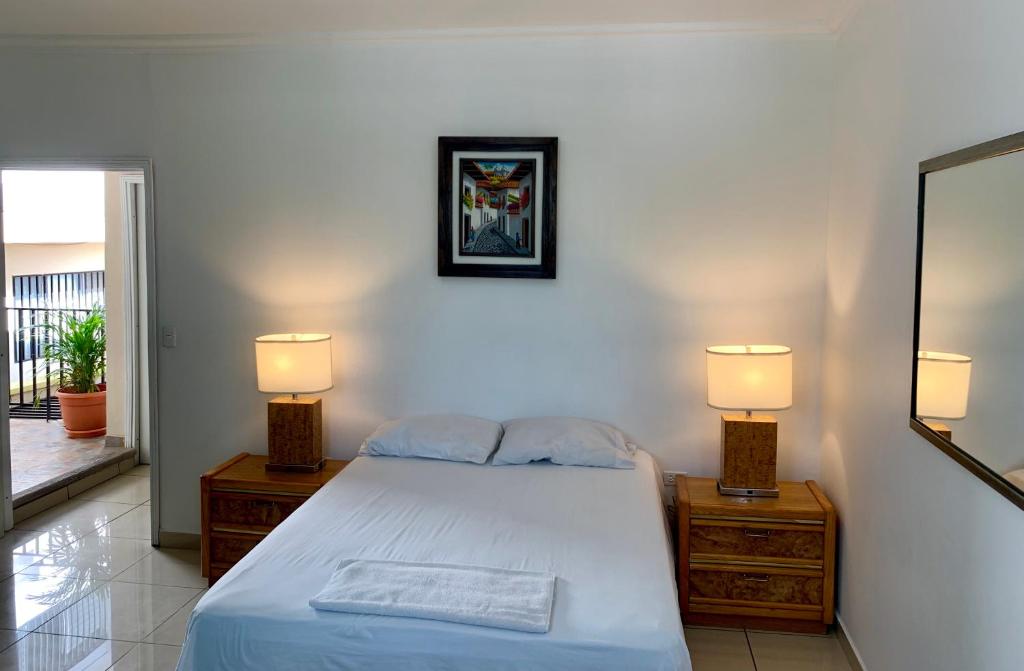 a bedroom with a bed and two lamps and a mirror at Palmira Hostel in Tegucigalpa
