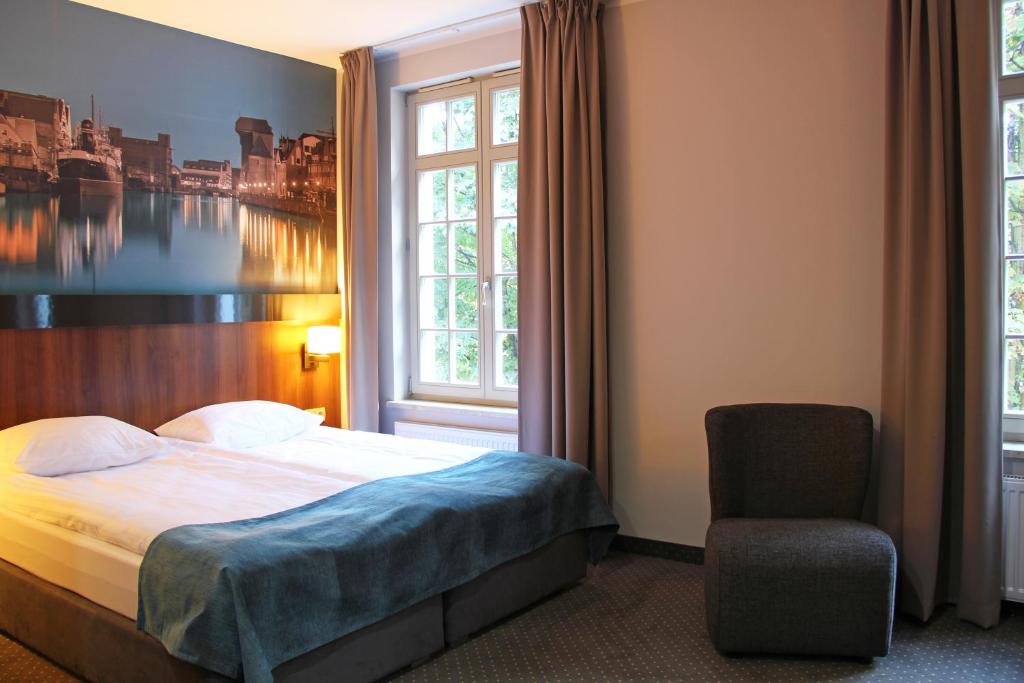 グダニスクにあるApart Neptunのベッドと椅子付きのホテルルーム