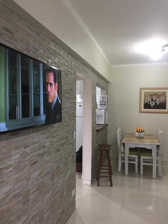 ein Wohnzimmer mit einem TV an einer Backsteinwand in der Unterkunft Enseada guaruja in Guarujá