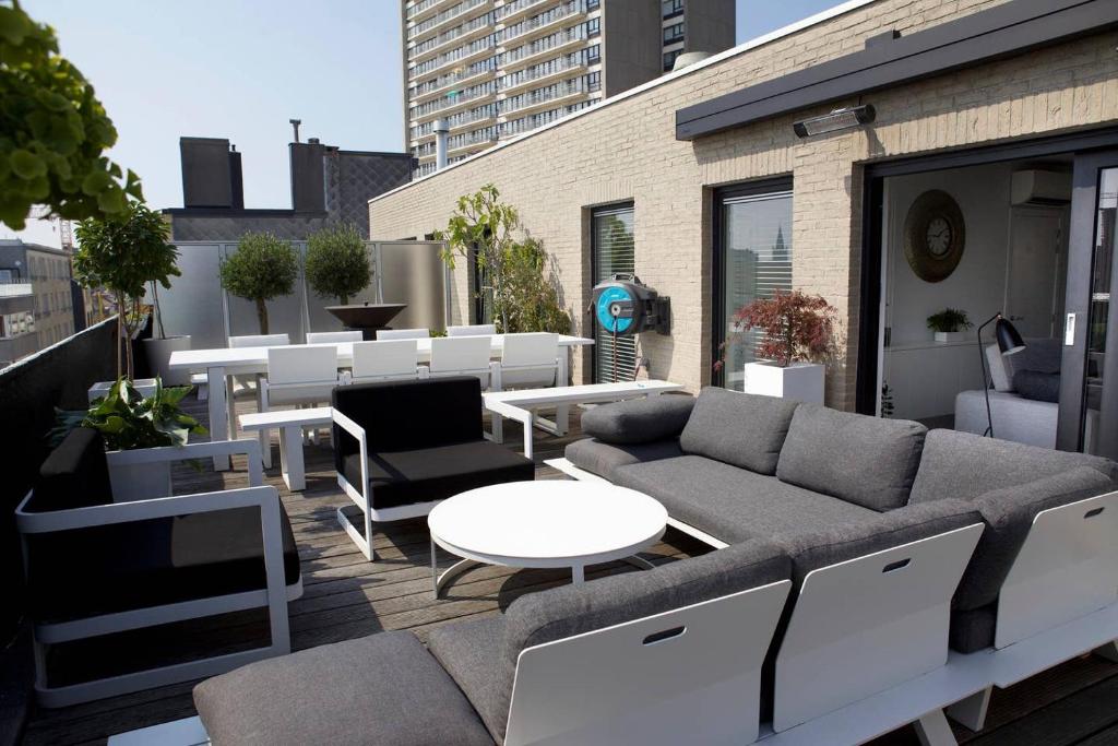 eine Dachterrasse mit einem Sofa, Tischen und Stühlen in der Unterkunft Modern appartement centrum Oostende met enorm dakterras (parking beschikbaar) in Ostende