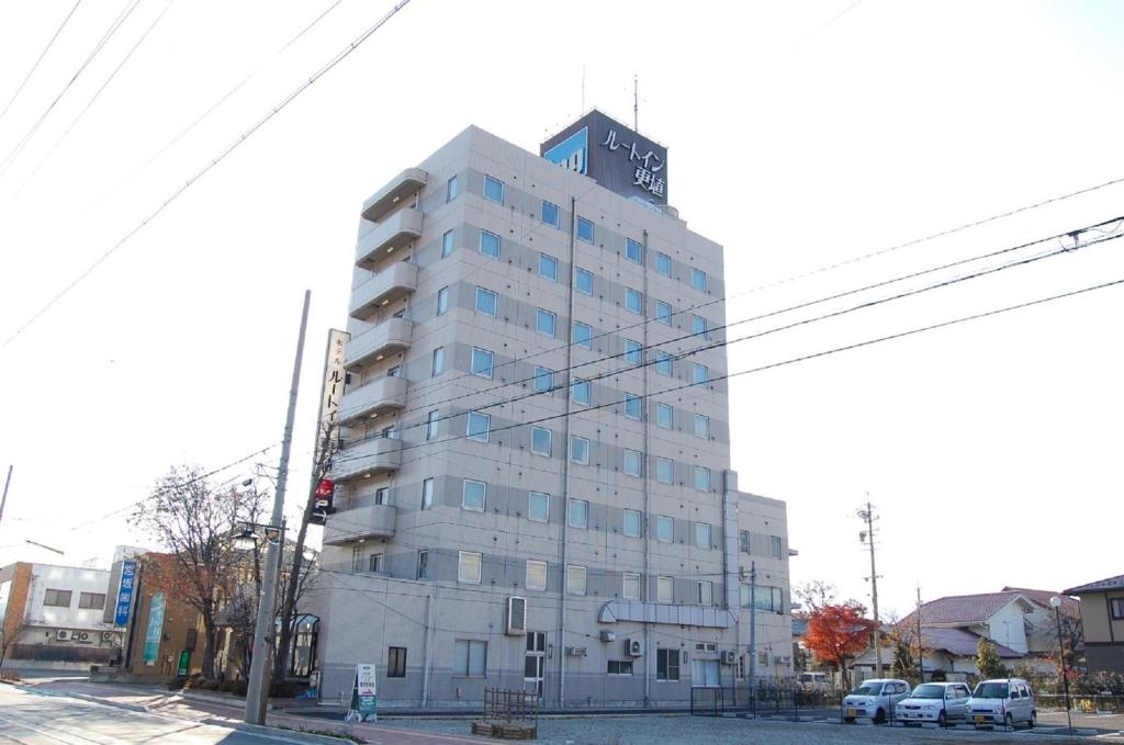 Hotel Route-Inn Court Chikuma-Koshoku في Chikuma: مبنى أبيض طويل مع ساعة عليه