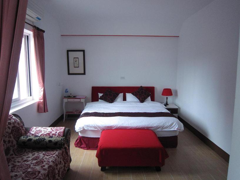 a bedroom with a large bed and a red ottoman at Amy Walker B&amp;B in Taimali