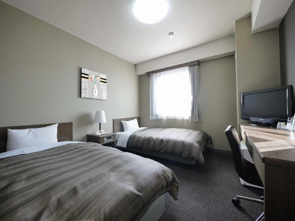 Habitación de hotel con 2 camas y TV de pantalla plana. en Hotel Route-Inn Myoko Arai, en Myoko