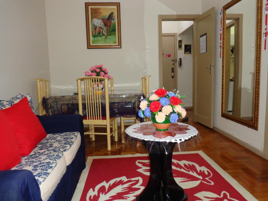 a living room with a couch and a table with flowers on it at Excelente Apartamento Copacabana in Rio de Janeiro