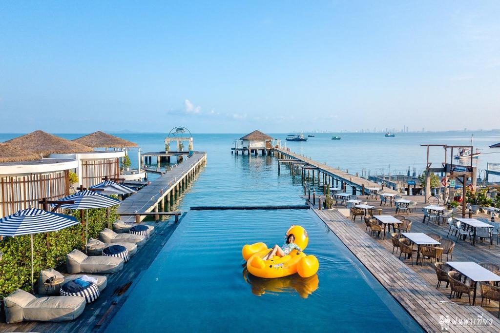 un radeau en caoutchouc jaune dans une piscine à côté d'une jetée dans l'établissement Kept Bangsaray Hotel Pattaya, à Bang Sare