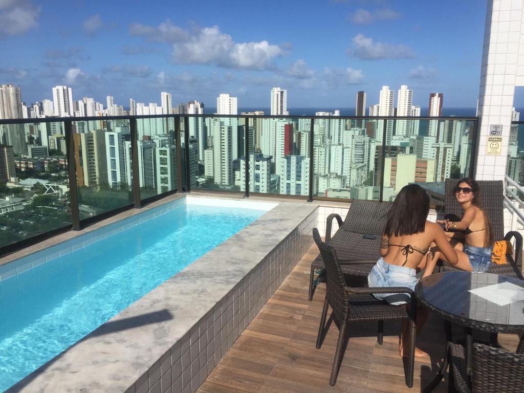 Dos mujeres sentadas en el balcón de un edificio en Golden Shopping Home Service en Recife