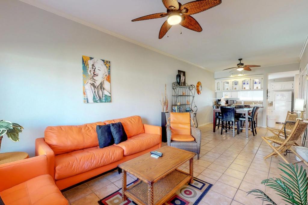 a living room with an orange couch and a table at Dolphin #22 in South Padre Island