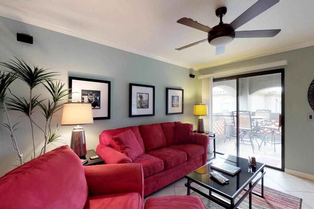 sala de estar con sofá rojo y ventilador de techo en Veranda at Ventana #30208, en Tucson