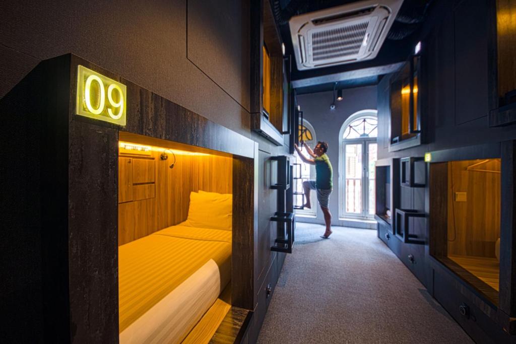 a woman is standing in a room with a bed at CUBE Boutique Capsule Hotel at Chinatown in Singapore
