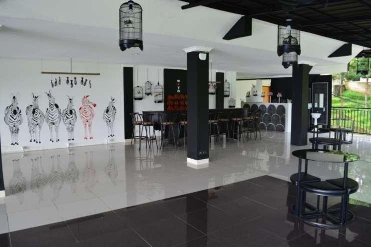 ein Zimmer mit Stühlen, Tischen und einer Wand mit Zeichnungen in der Unterkunft Albero Hotel Bogor in Bogor