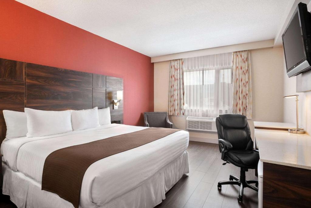 um quarto de hotel com uma cama grande e uma secretária em Baymont by Wyndham Medicine Hat em Medicine Hat