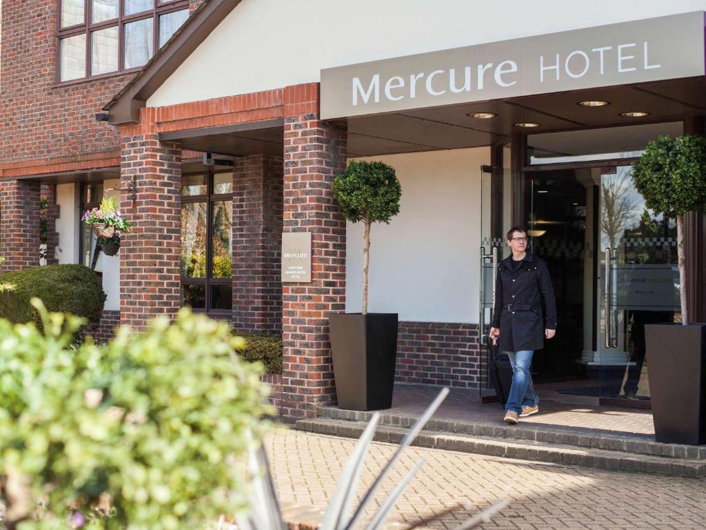 Um homem está a sair de um hotel misericordioso. em Mercure Dartford Brands Hatch Hotel & Spa em Ash