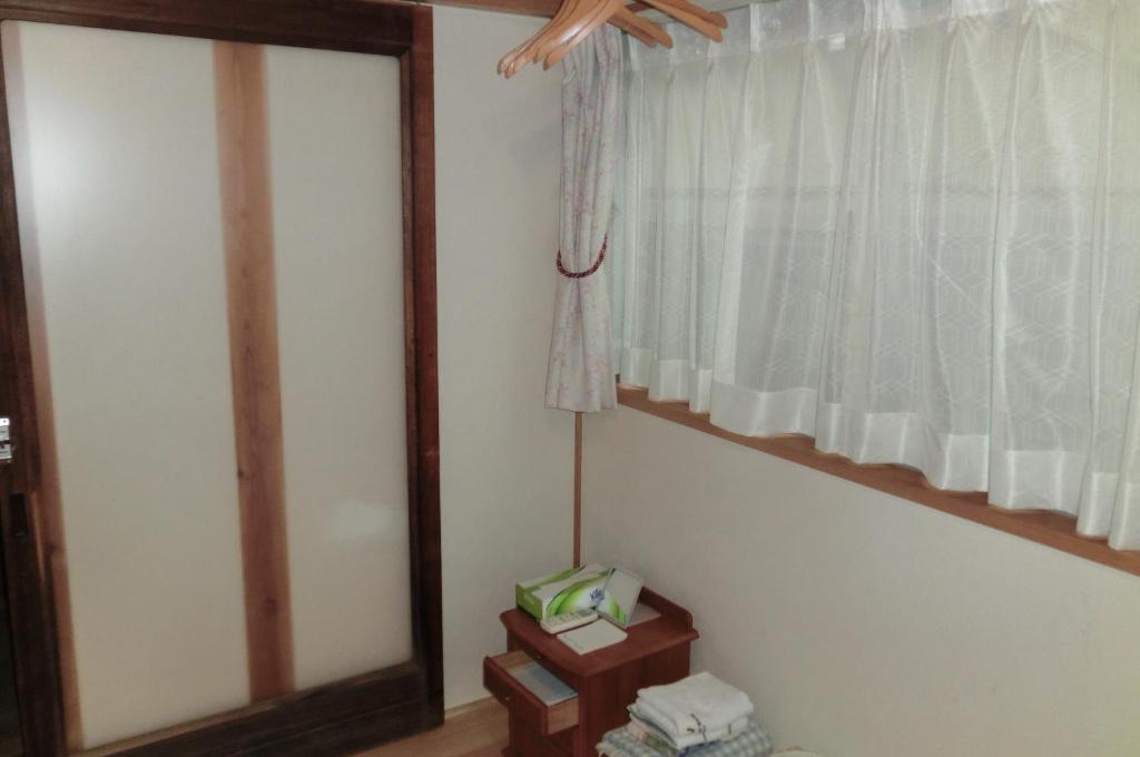 um quarto com uma janela e um candeeiro sobre uma mesa em 交流の宿 em Musashino