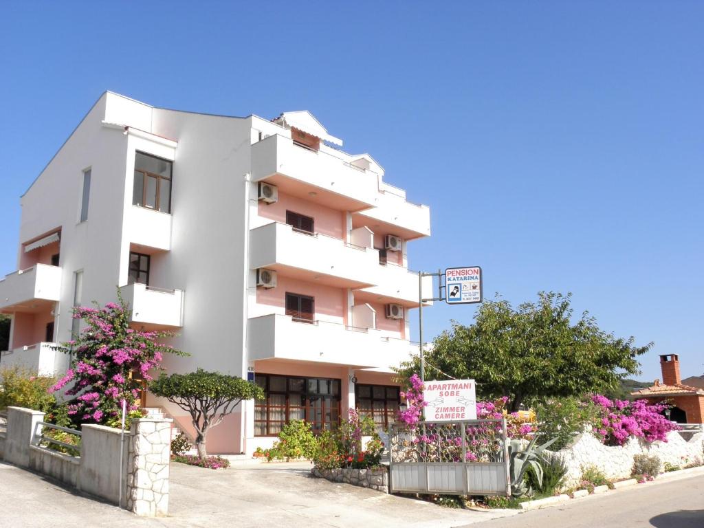 a white building with flowers in front of it at Apartments Katarina in Sveti Petar
