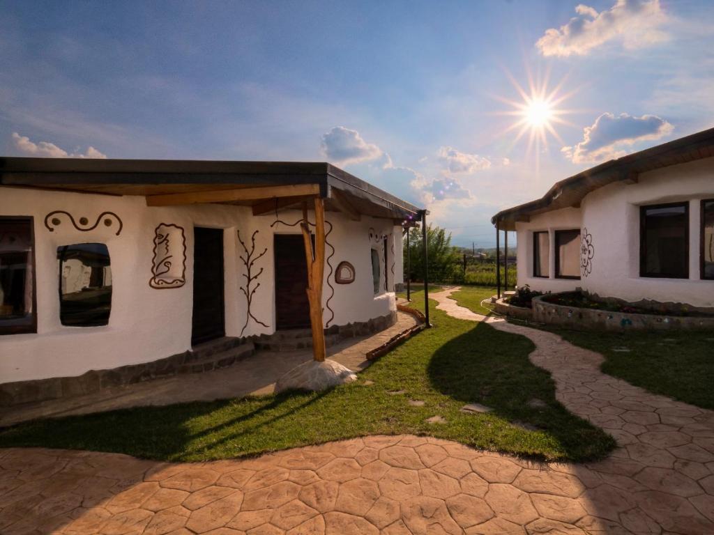 a house with the sun in the sky at Cob Village in Berca