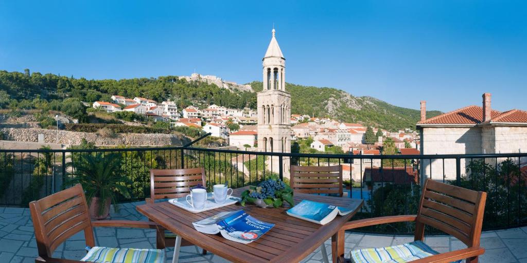 uma mesa de madeira e cadeiras numa varanda com uma cidade em Apartments Olive Tree em Hvar