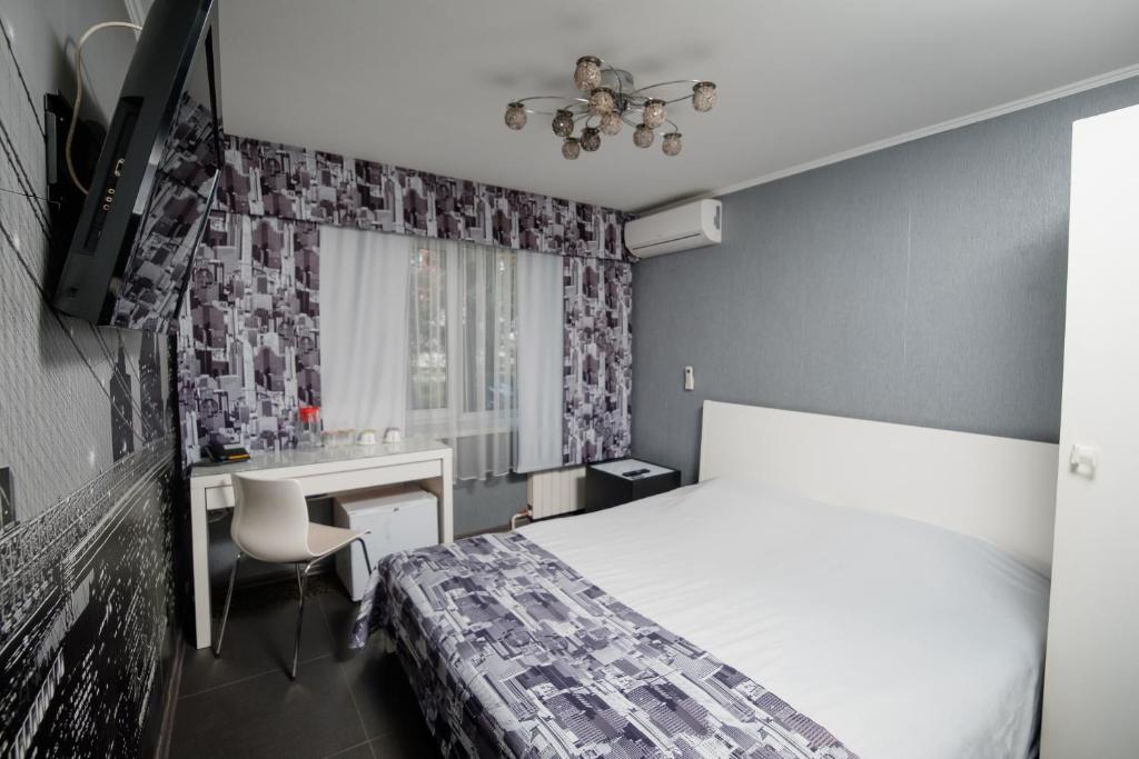 a bedroom with a bed and a desk and a window at Aurooms in Novokuznetsk