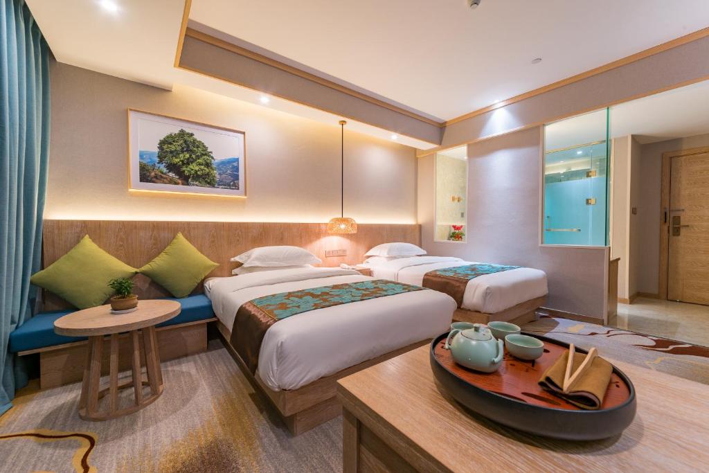 a hotel room with two beds and a table at Yunxianju Tea Culture Theme Hotel in Kunming