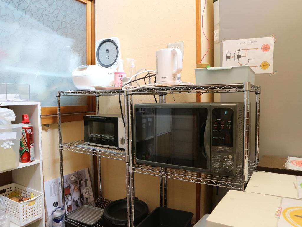 a microwave on a metal rack in a kitchen at Guest House Minato in Miyako