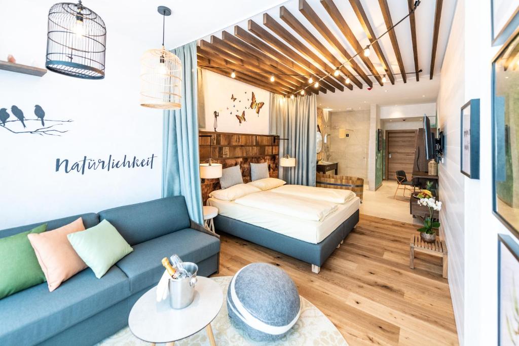 ein Wohnzimmer mit einem Bett und einem Sofa in der Unterkunft Hotel Vier Jahreszeiten Loipersdorf in Loipersdorf bei Fürstenfeld