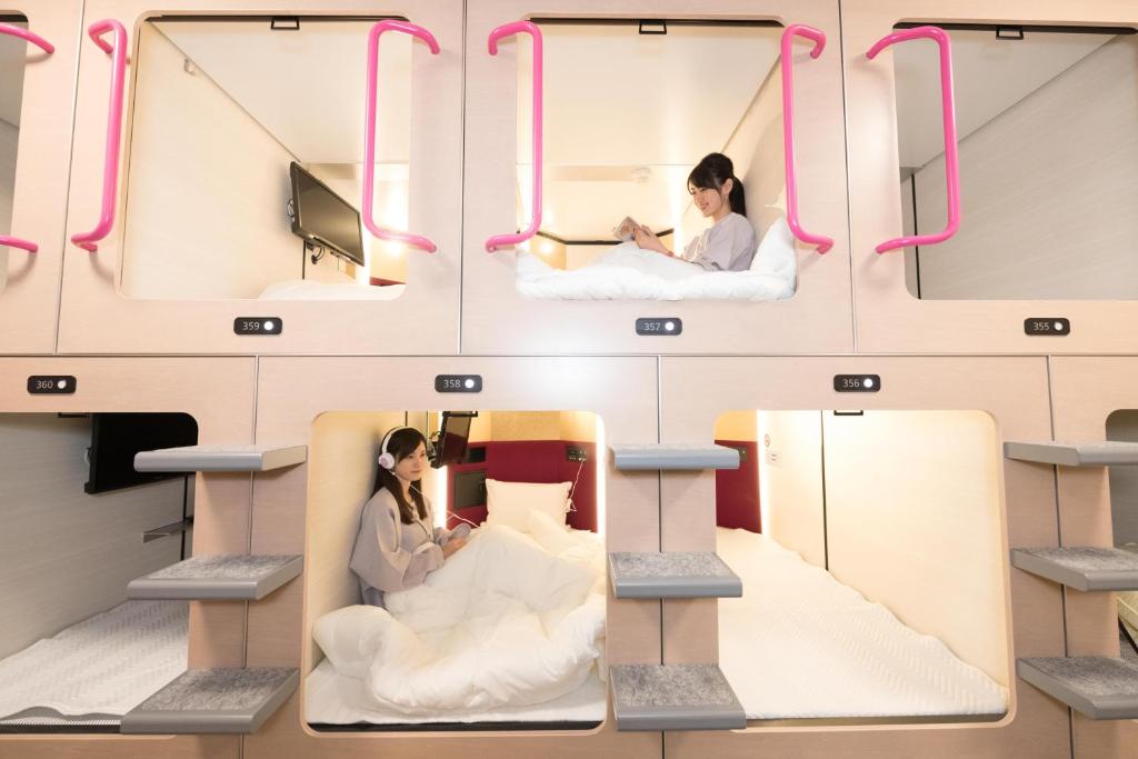 une chambre avec 2 personnes dans des lits avec des poignées roses dans l'établissement Matsue Urban Hotel CubicRoom, à Matsue