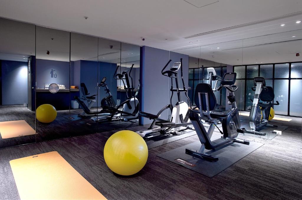 a gym with exercise equipment and a large mirror at Just Sleep - Ximending in Taipei