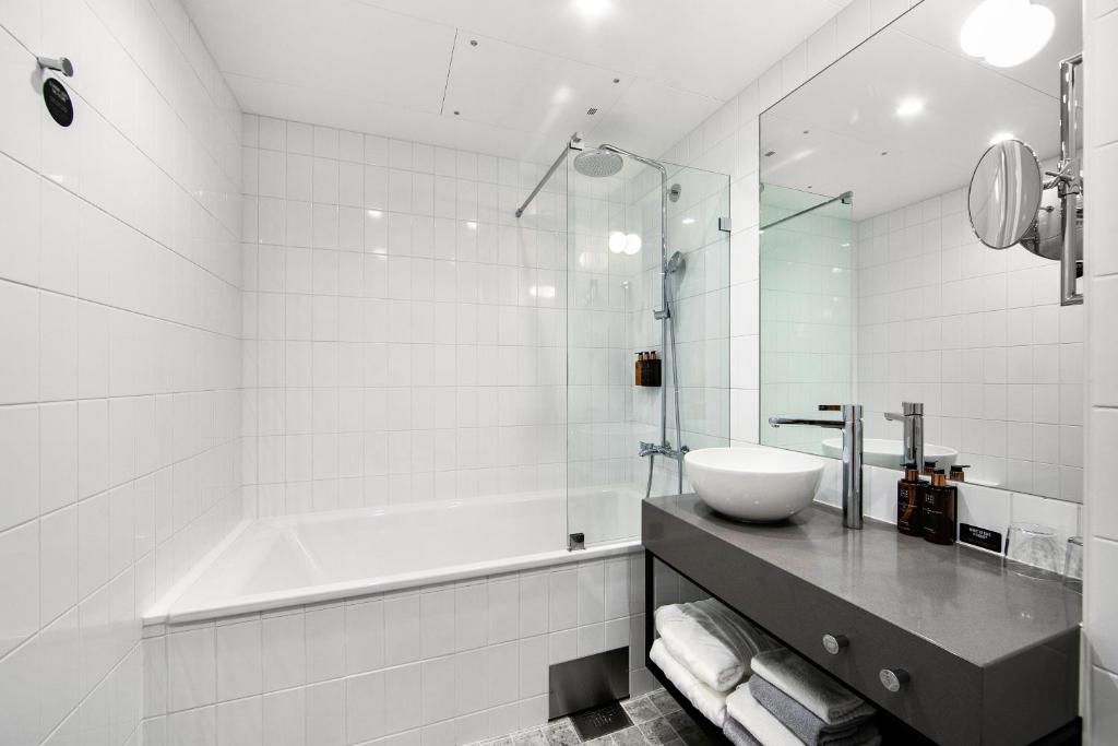 a bathroom with a tub and a sink and a bath tub at Clarion Hotel Oslo in Oslo