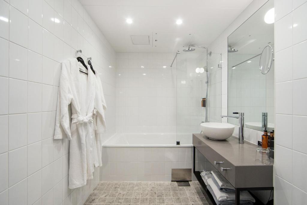 a white bathroom with a tub and a sink and a bath tubermott at Clarion Hotel Oslo in Oslo