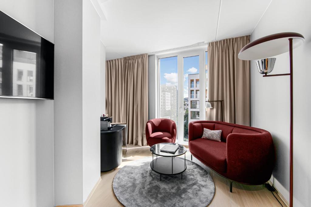 a living room with two red chairs and a table at Clarion Hotel Oslo in Oslo