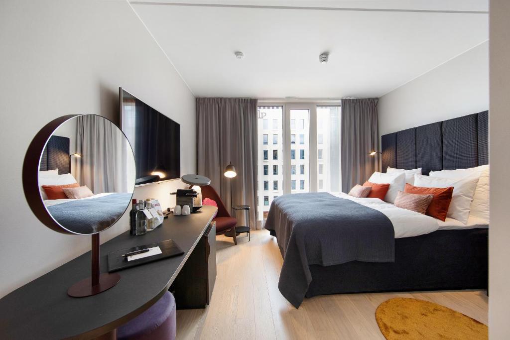 a hotel room with a large bed and a mirror at Clarion Hotel Oslo in Oslo
