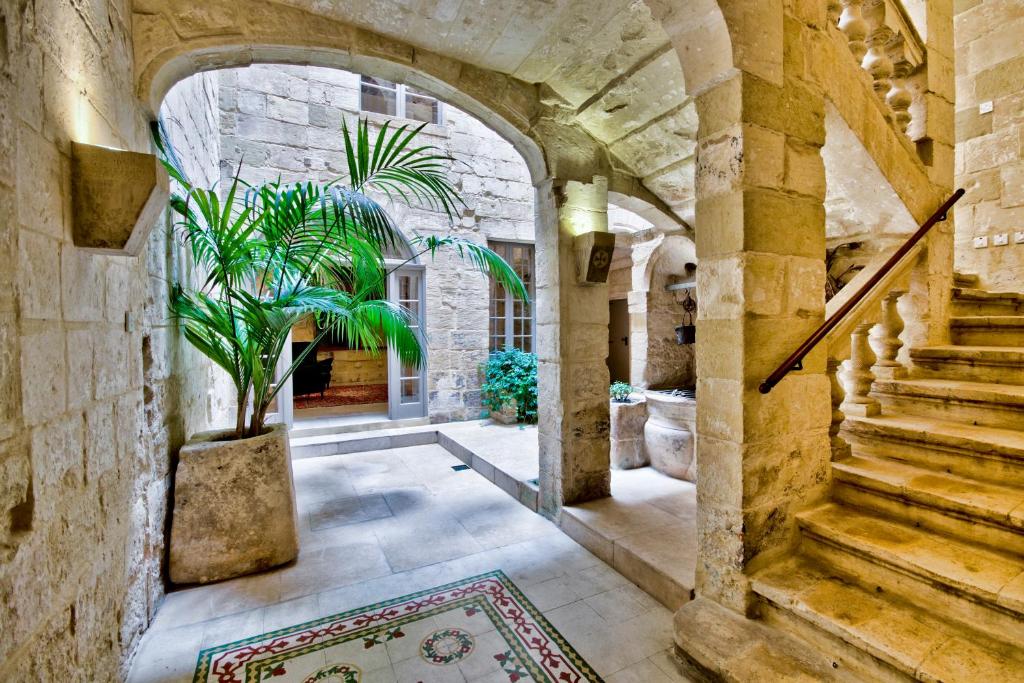 kamienny korytarz ze schodami i doniczką w obiekcie Vallettastay Palazzo Rose of Rhodes w mieście Valletta