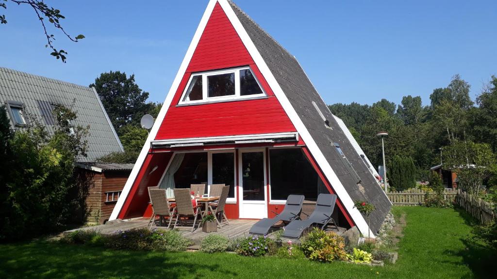 a red and white triangular house with chairs and a table at Ostseepirat in Damp