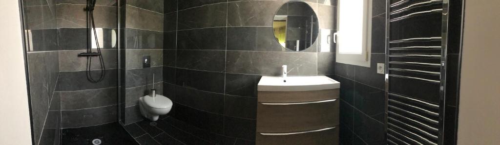 a black tiled bathroom with a sink and a mirror at Maxima Sunset in Sainte-Maxime