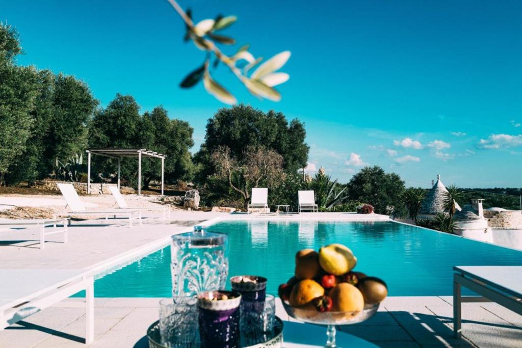 uma taça de fruta sentada ao lado de uma piscina em Relais Trulli Le Icone em Ostuni