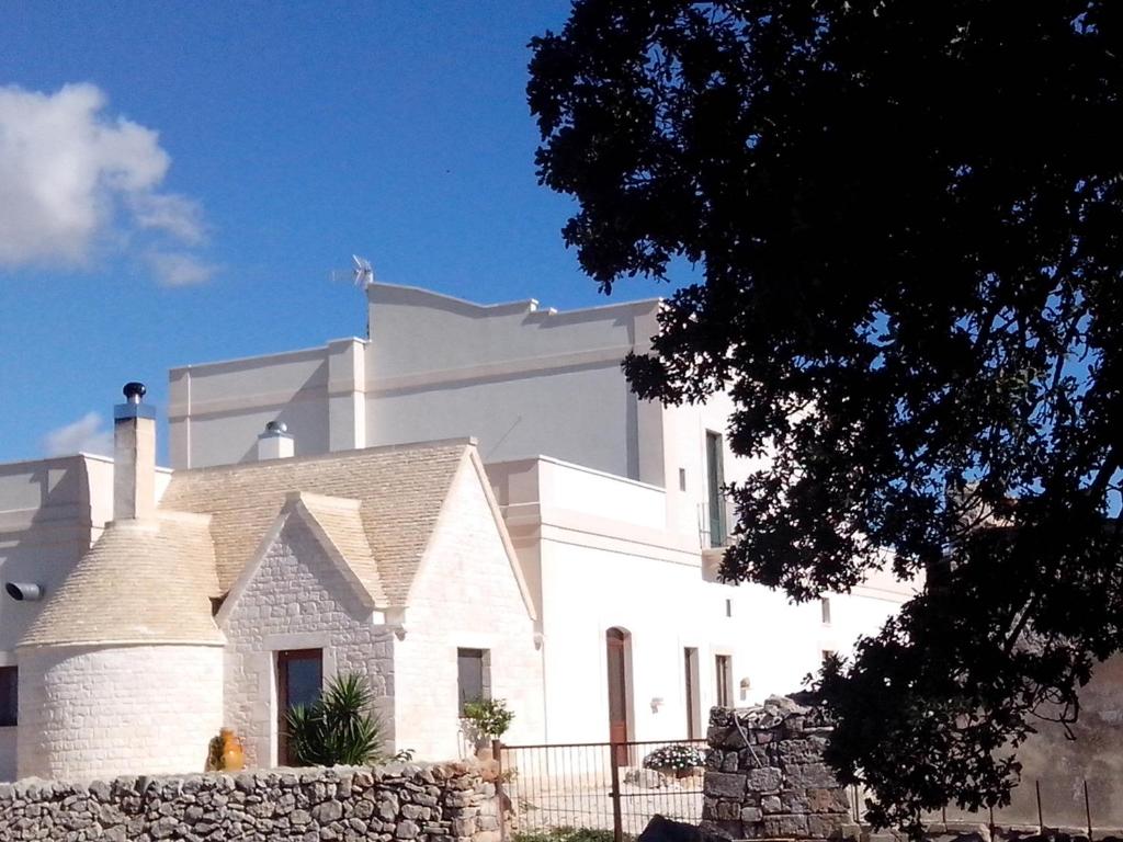 a white building with a stone wall in front of it at Masseria Ciavea in Gioia del Colle