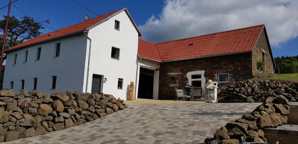 a white building with a red roof and a stone wall at Waldhaus Nearby Nürburgring in Bongard